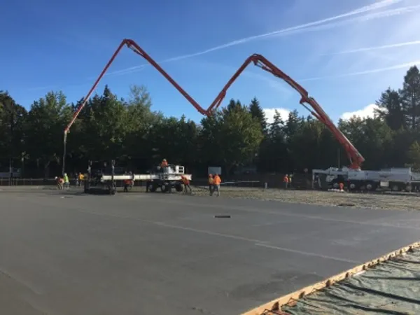 Two concrete pumper trucks on a large outdoor slab pour
